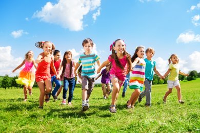 Rennende Kinder mehrere Kinder die über eine Wiese laufen