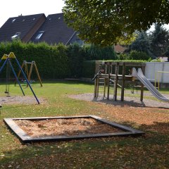 Spielplatz mit Sandkasten, Rutsche und Schaukel