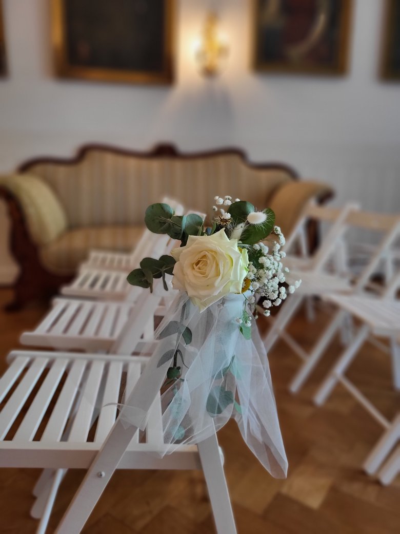 Stuhl mit Blumendeko weißer Stuhl mit Blumendeko im Hintergrund ist ein Sofa zu sehen