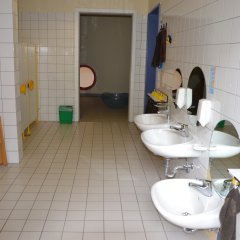 Waschraum mit drei Waschbecken und Zahnputzbechern