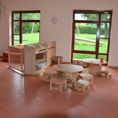 Gruppenraum Kinderkrippe mit Tischen und Stühlen