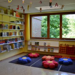 Bibliothek mit Büchern, Regalen und Sitzkissen auf dem Boden